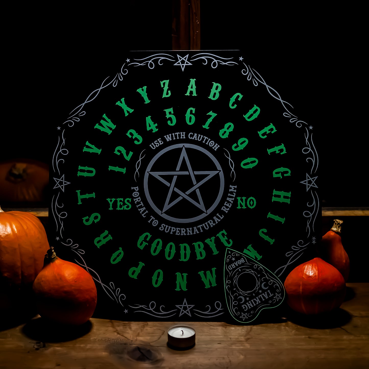 Ein Ouija-Brett, das im Dunkeln leuchtet, mit leuchtenden Buchstaben von A bis Z und Zahlen von 0 bis 9. In der Mitte befindet sich ein Pentagramm, umgeben von den Worten ‘YES’ und ‘NO’. Unten stehen die Wörter ‘GOODBYE’. Das Brett wird durch ein mystisches grünes Leuchten hervorgehoben.
