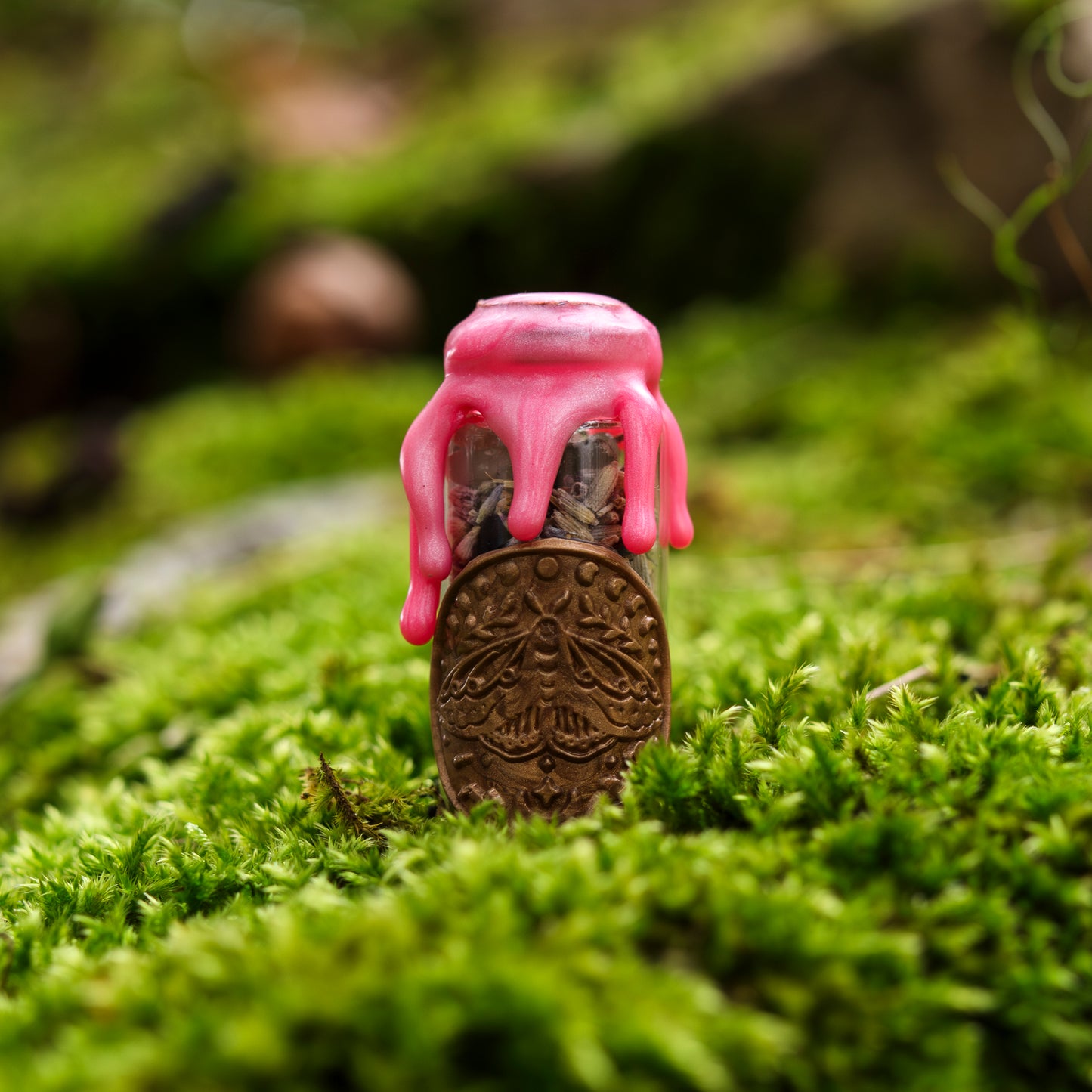 Kleine Spelljar ‚Selbstliebe‘ mit rosa Wachsversiegelung und einem dekorativen Anhänger mit geprägtem Motiv, auf moosbedecktem Untergrund präsentiert.