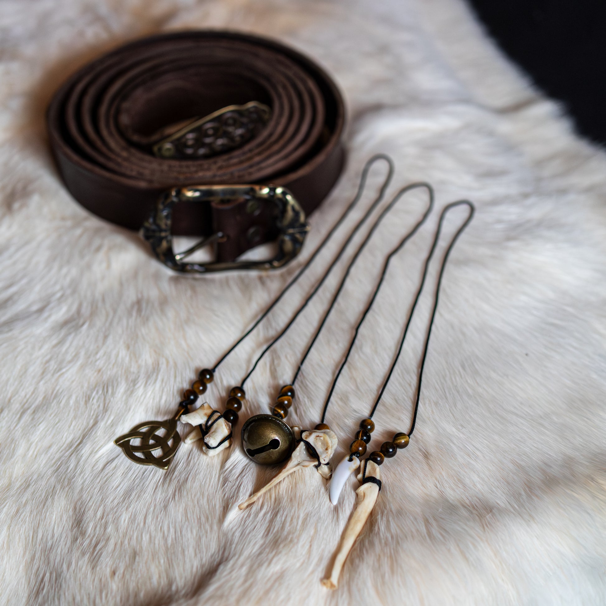 Handgefertigte Gürtelcharms mit Tigerauge, Knochen und keltischer Symbolik für Mut, Schutz und innere Stärke.