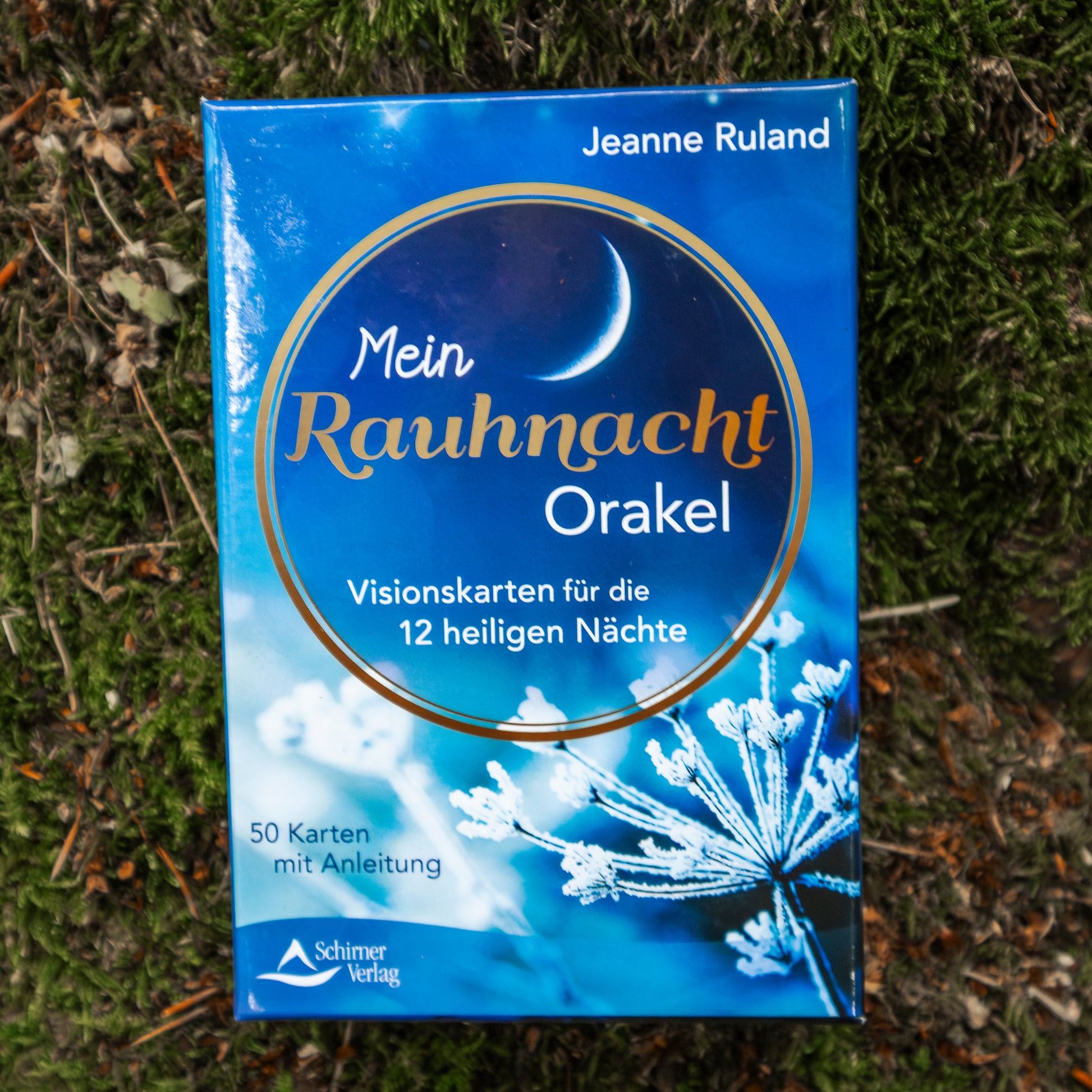 Das Orake-Set ‘Mein Rauhnacht Orakel’ mit Visionskarten für die 12 heiligen Nächte, auf einem moosbedeckten Waldboden arrangiert.